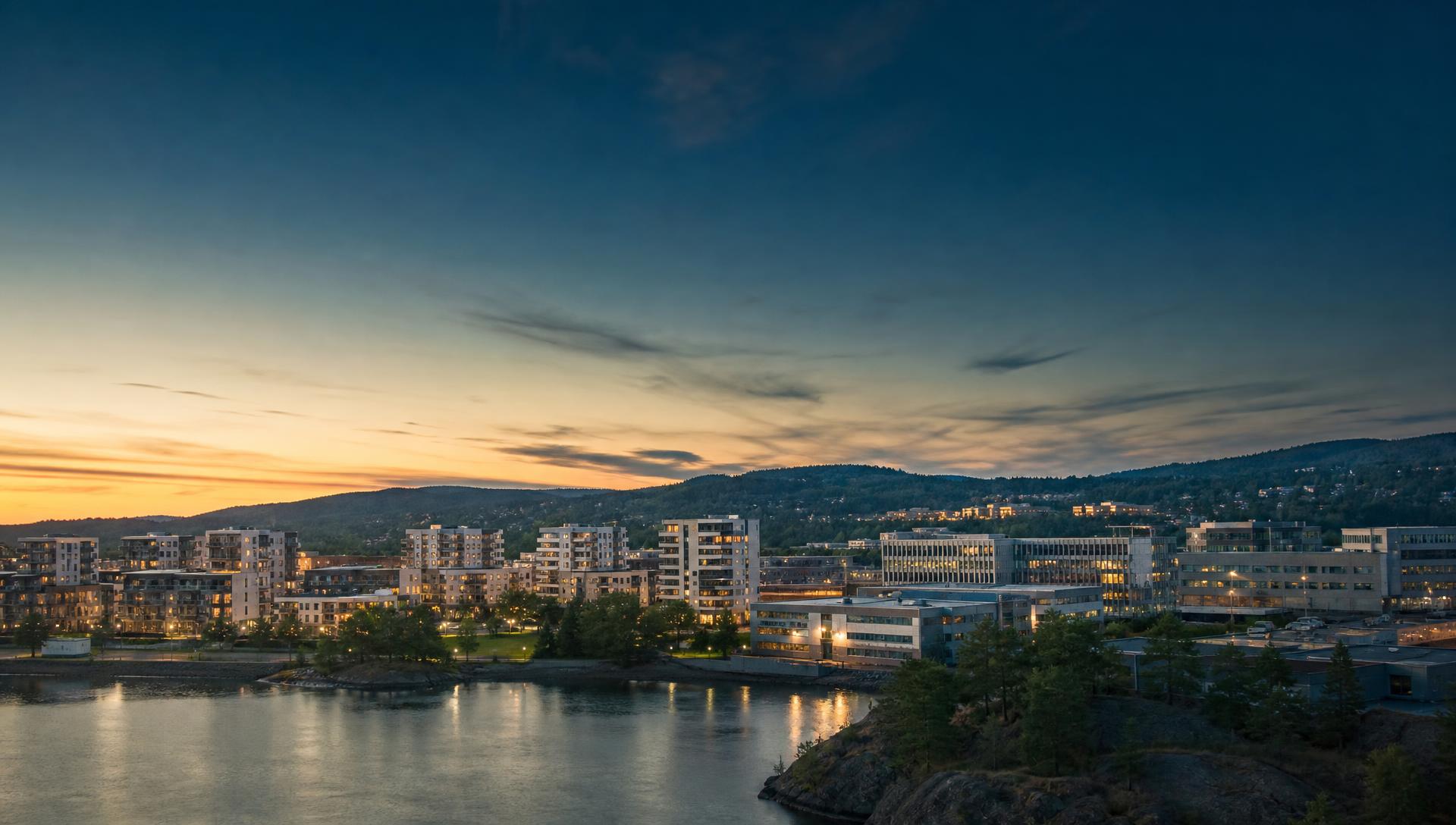 A Swedish small town at dusk, with homes, offices and industrial buildings beside the water