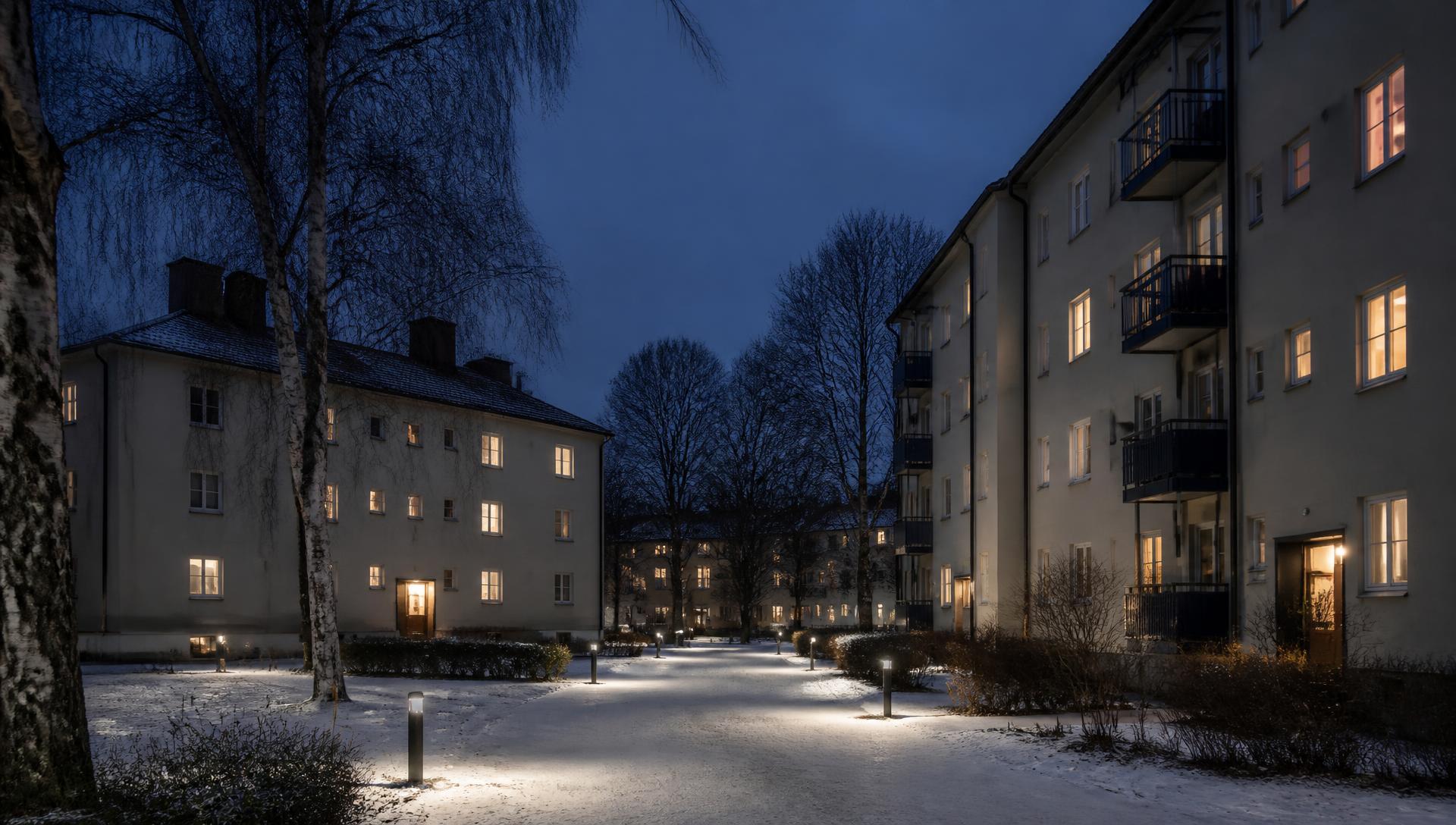 A small Nordic town at dusk in winter, with warm lights in the windows and street lighting along a quiet snow-covered street